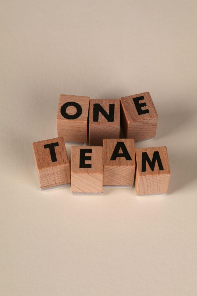 Bloc de bois formant le mot One Team, symbole de cohésion et d’accompagnement collectif en management