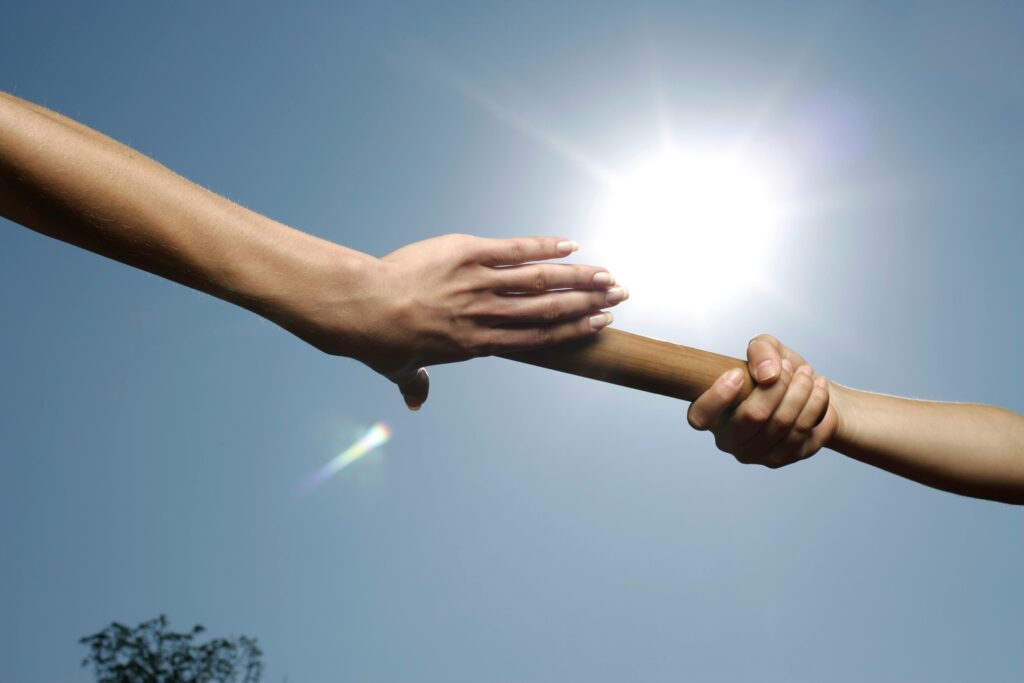 Deux mains se passant un relais, métaphore de l’accompagnement des dirigeants et managers